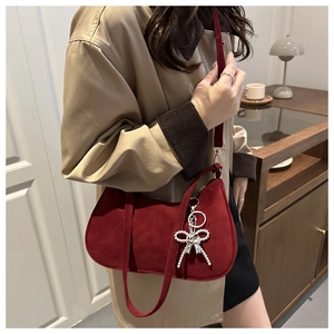 Gros plan détaillé d'un sac baguette bordeaux en daim avec un charm noeud en perles