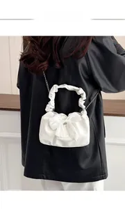 Detail der weißen Plissee-Handtasche mit großer Schleife und Wolkengriff mit Silberkette