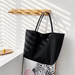 Detailed view of black canvas bucket tote bag hanging on wooden hook with shadow play