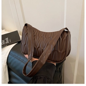Detail of deep brown pleated quilted faux leather surface on underarm shoulder bag