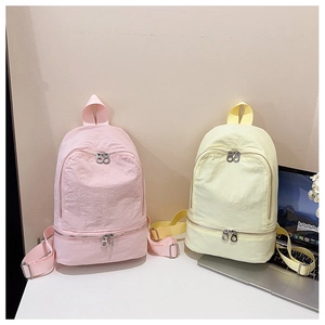Détail de sacs à dos en nylon froissé rose et jaune avec zips argentés et sangles tissées