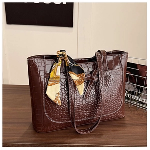 Close-up of deep brown crocodile-embossed tote bag with decorative floral silk scarf
