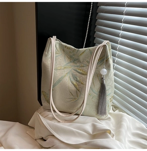 Detailed texture of jacquard tote bag with bamboo leaves, birds, and silk tassel detail