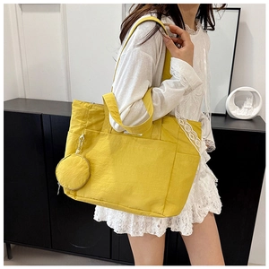 Detailed close-up of a bright yellow nylon tote bag with round coin purse and zipper pocket