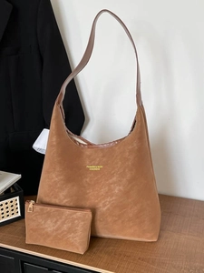 Brown suede hobo bag with matching mini pouch on a wooden table with soft lighting