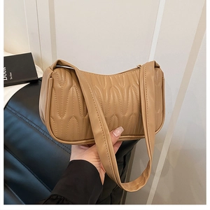 Detailed close-up of khaki pleated underarm bag showing quilted texture and curved handle