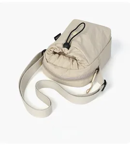 Dettaglio della mini borsa a tracolla in nylon beige con coulisse e tasca con zip