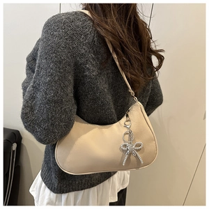 Détail du sac hobo beige montrant le pendentif cœur en métal et la texture cuir mat