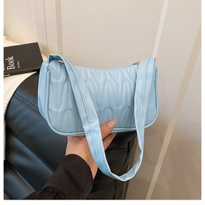 Detailed close-up of light blue underarm bag with unique wave quilted pleated texture