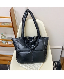 Detail view of black quilted puffer tote bag in glossy water-repellent nylon material