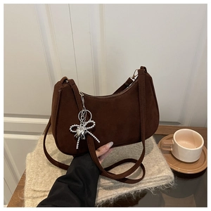 Détail du sac baguette en daim marron foncé avec pendentif nœud en perles argentées