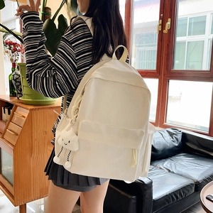Detail view of large white canvas backpack with fluffy cloud pendant on model