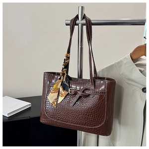 Detailed view of dark brown croc-embossed tote bag with decorative silk scarf and buckles