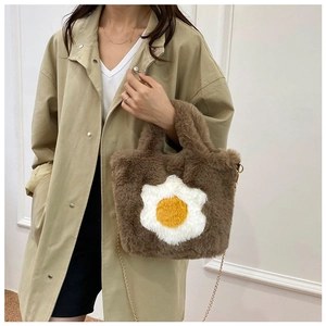 Detail view of brown plush crossbody bag with fried egg pattern and chain strap