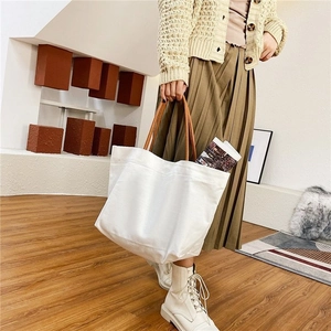 Close-up of white canvas bucket bag with brown leather handles for daily commute style