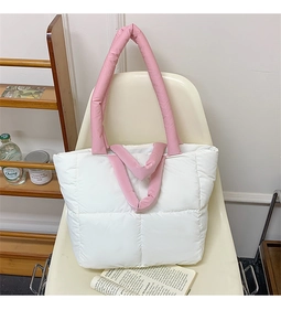 Detail of white quilted tote bag with pink padded handles on a white chair