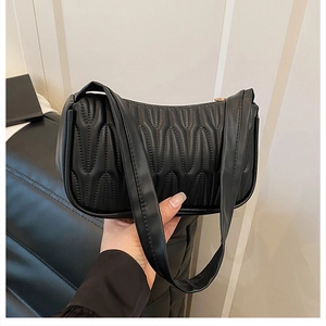 Detailed macro view showing vertical wave quilted texture on the black PU leather shoulder bag