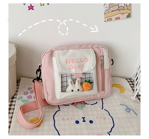 Détail du sac bandoulière en toile rose avec poche PVC et adorable peluche de lapin