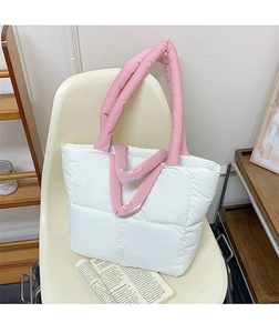 Quilted puffer tote bag detail with white body and soft pink handles on a chair