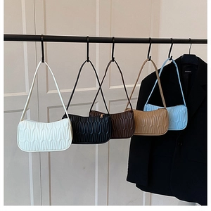 Detail view of mini pleated underarm bags in five colors on a professional display