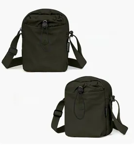 Dettaglio della borsa in nylon verde scuro con chiusura a coulisse e logo frontale