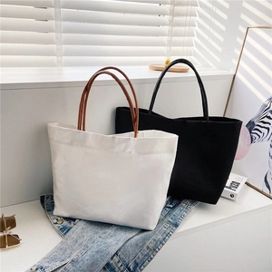 Detail view of black and white minimalist canvas bucket bags on a styled white surface
