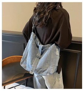 Detail view of slouchy denim shoulder bag showing vintage distressed edges and large capacity