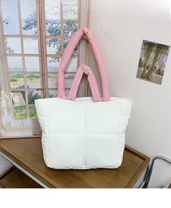 Quilted puffer tote bag detail showing pink straps and white matte fabric in home setting