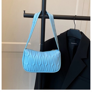Detail of light blue quilted underarm bag with wave texture and zipper closure