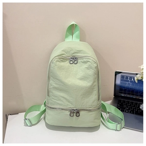 Détail du sac à dos en nylon vert clair montrant les fermetures éclair et compartiments