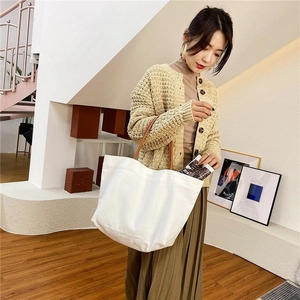 Detail of white canvas bucket bag with brown straps styled on model with a long skirt
