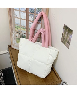 Close-up of white quilted puffer tote bag with pink padded handles on a wooden desk