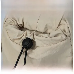 Dettaglio della chiusura a coulisse in nylon beige con fermacorda nero sulla borsa