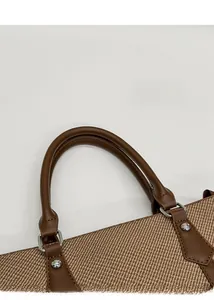 Detailaufnahme der braunen Ledergriffe mit Silbernieten an einer gewebten Damenhandtasche