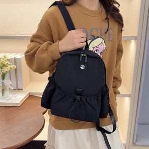 Nahaufnahme des schwarzen wasserdichten Nylon-Rucksacks mit Metalllogo und Kordelzug
