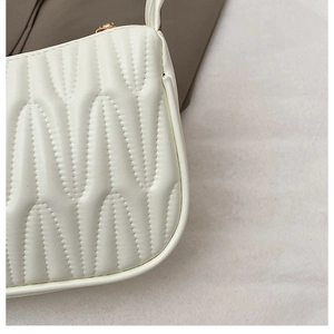 Close-up of white quilted leather texture with gold zipper on a French mini baguette bag