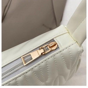 Detailed close-up of cream quilted mini bag showing gold zipper and wavy PU leather texture