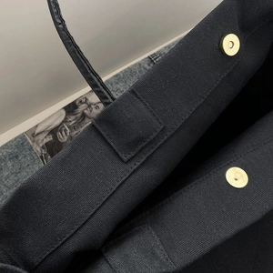 Detail view of the secure magnetic gold clasp and stitching on the black canvas tote bag