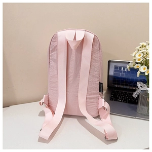 Vue détaillée des bretelles et de l'étiquette de la marque du sac à dos rose