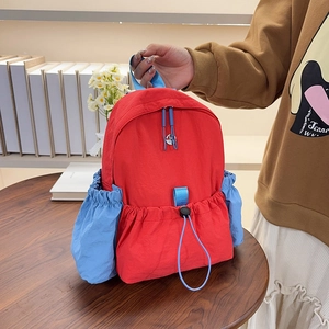 Detailansicht eines rot-blauen Nylon-Rucksacks mit Kordelzug und metallischem Logo