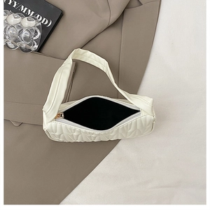 Close-up of white quilted underarm bag with gold zipper and black fabric lining detail