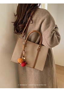 Braune gewebte Tragetasche an einem Modell mit herbstlichem Styling und Quastenanhänger