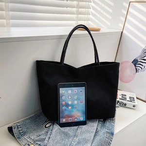 Detail of spacious black canvas bucket bag with tablet showing large storage capacity