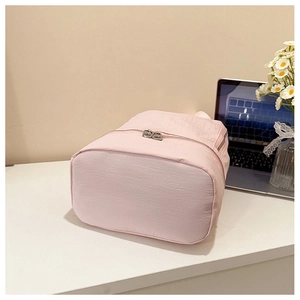 Détail du bas du sac à dos en nylon rose avec fermeture à glissière double sur table
