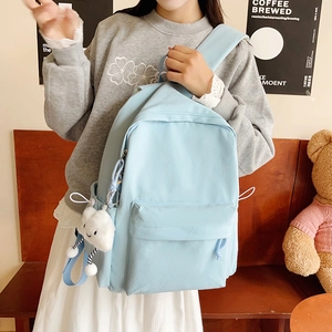 Detail of light blue canvas backpack with cute white cloud plush pendant accessory