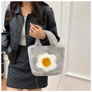 Detail of grey plush crossbody bag with fried egg decor and golden chain strap