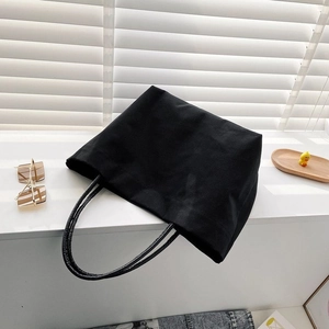 Detail shot of a black canvas bucket bag on a bright windowsill with natural lighting