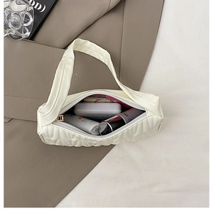 Internal view of cream quilted shoulder bag showing capacity for cosmetics and lipsticks