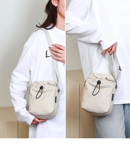 Dettaglio della borsa a tracolla in nylon beige con chiusura a coulisse e logo