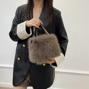 Dettaglio borsa di peluche marrone scuro con anelli dorati e manico in pelle su modella